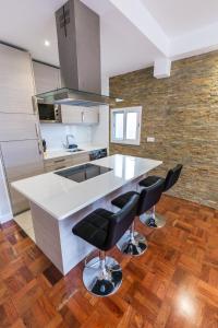 a kitchen with a white counter and black chairs at Sea Breeze II in Caniço