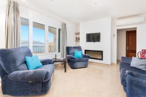 een woonkamer met twee blauwe stoelen en een televisie bij Sunset Villa Nixe in Alcudia