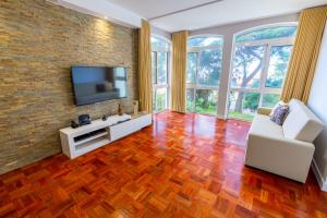 a living room with a television on a brick wall at Sea Breeze II in Caniço