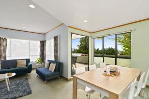 a living room with a wooden table and chairs at Red Door holiday house in Rotorua
