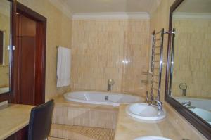 baño grande con bañera y lavamanos en Emangunini Guest house, en Richards Bay
