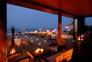 un restaurante con mesas y sillas en la playa por la noche en Hotel President, en Silvi Marina