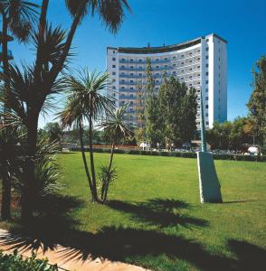 a park with palm trees and a large building at Hotel President in Silvi Marina