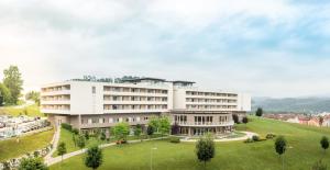 un gran edificio blanco con un parque enfrente en Hotel und Therme NOVA, en Köflach