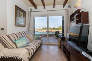 a living room with a couch and a flat screen tv at Menurka - Cala Blanca in Cala Blanca