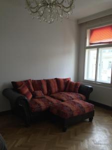 ein Ledersofa im Wohnzimmer mit einem Kronleuchter in der Unterkunft Apartman Vridelni 136 Karlovy Vary in Karlsbad