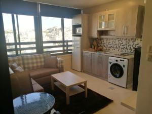 a living room with a couch and a kitchen with a washing machine at Dair Ghbar Gate Apartments in Amman