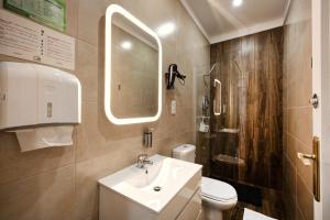 a bathroom with a toilet, sink, and mirror at Loulé Coreto Guesthouse in Loulé