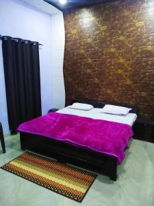 a bedroom with a bed with a purple blanket at Radha Krishna Dham in Vrindāvan