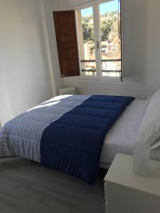 a bedroom with a blue bed with a window at Apartament L'Alba in Tossa de Mar