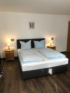 1 cama con sábanas blancas y almohadas en una habitación en Hotel Guntia Boardinghouse, en Günzburg