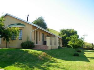 a house with a grass yard in front of it at Thaba Tsweni Lodge & Safaris in Graskop