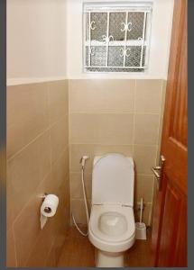 a small bathroom with a toilet and a window at Palm Valley in Nairobi