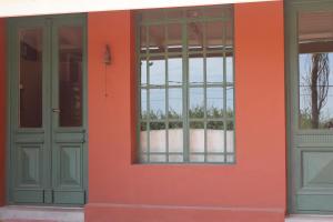 un edificio rojo con una puerta verde y ventanas en Quinta El Monte en Tandil