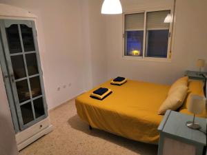 um quarto com uma cama amarela e uma janela em Vivienda cercana a la playa con todas las comodidades em Tarifa