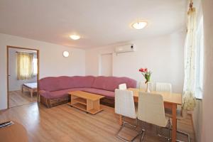 ein Wohnzimmer mit einem lila Sofa und einem Tisch in der Unterkunft Apartmani Bradaric in Pula