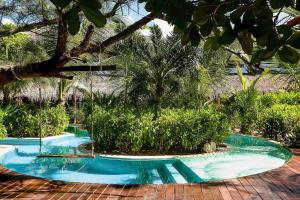 a swimming pool in the middle of a garden at The Beach Tulum Hotel in Tulum