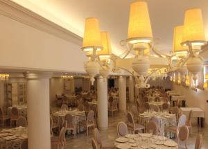 a banquet hall with tables and chairs and a chandelier at Hotel Reyes Ziries in Albolote