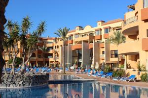 - une piscine avec des chaises longues et des palmiers dans l'établissement Grand Muthu Golf Plaza Hotel & Spa, à San Miguel de Abona