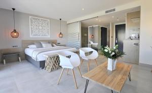 a bedroom with a bed and two white chairs at Le Spinaker in Le Grau-du-Roi