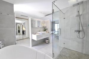 a white bathroom with a sink and a shower at Le Spinaker in Le Grau-du-Roi