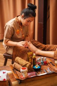 a woman is getting a foot massage on a persons leg at HARRIS Hotel Batam Center in Batam Center