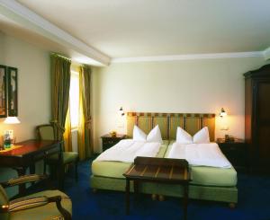 Una habitación de hotel con una cama con sábanas blancas y una mesa. en Brutsches Rebstock en Laufenburg