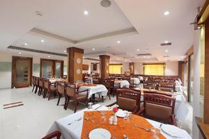 a restaurant with tables and chairs in a room at Hotel Anjali Park in Kottayam
