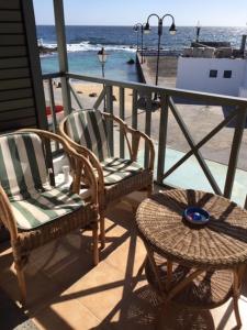 einen Balkon mit 2 Stühlen, einem Tisch und dem Strand in der Unterkunft Apartamento El Muelle in Arrieta