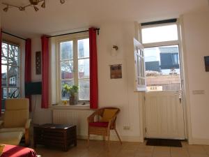 una sala de estar con 2 ventanas y una silla en Dar Cho Apartment en Zandvoort