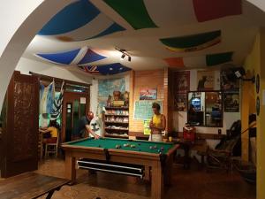 two people playing pool in a room with a pool table at Geckos Hostel in Florianópolis