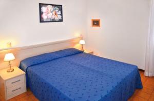 1 cama azul en un dormitorio con 2 lámparas en Villaggio Capistrano, en Bibione