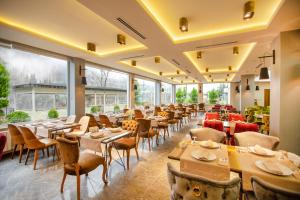 ein Restaurant mit Tischen, Stühlen und Fenstern in der Unterkunft Jolnar garden hotel in Macka