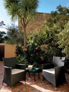 een patio met 2 stoelen, een tafel en een palmboom bij Carrer Dels Horts in Alghero