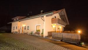 a white house with a balcony at night at Haus Osserblick in Arrach