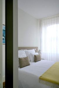 a bedroom with a large white bed with a window at Mayor's Apartments in Porto