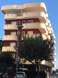 ein hohes Gebäude mit einem Baum davor in der Unterkunft Residenza Mediterraneo in Bellaria-Igea Marina