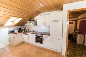 アルラッハにあるHaus Osserblickの白いキャビネットと木製の天井が備わるキッチン