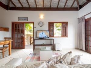 uma sala de estar com um sofá e uma televisão em Pousada Perequê em Ilhabela