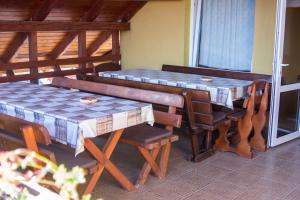 a porch with two tables and chairs and a window at Hazanéző Panzió in Corund