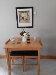 einen Holztisch mit zwei Tassen und eine Vase mit Blumen in der Unterkunft An Crann Glas in Galway