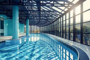 a large swimming pool in a large building at Corendon Urban Amsterdam Schiphol Airport Hotel in Badhoevedorp