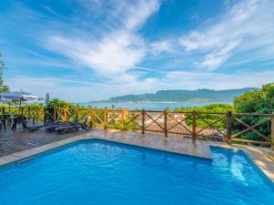 a swimming pool with a fence and a view of the water at Pousada Perequê in Ilhabela