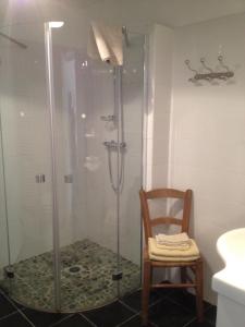 uma cabina de duche em vidro na casa de banho com uma cadeira de madeira em B&B Château Pierre de Lune em Saint-Émilion