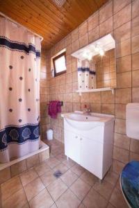 ein Bad mit einem Waschbecken, einem Spiegel und einer Dusche in der Unterkunft Apartmani Lovrinović in Vodice