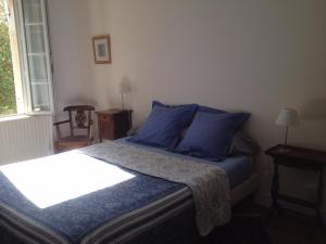um quarto com uma cama com almofadas azuis e uma janela em B&B Château Pierre de Lune em Saint-Émilion