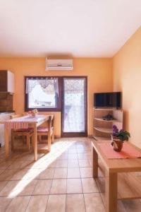 ein Wohnzimmer mit einem Tisch und einer Küche in der Unterkunft Apartmani Lovrinović in Vodice