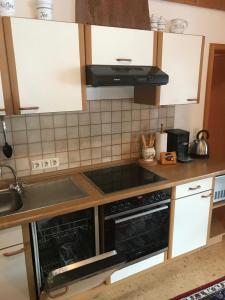 a kitchen with white cabinets and a stove top oven at Ferienwohnung Hubertus in Bischofsmais