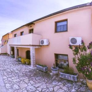 ein rosafarbenes Gebäude mit Fenstern und Pflanzen davor in der Unterkunft Apartmani Lovrinović in Vodice