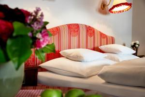 2 Betten mit weißen Kissen in einem Schlafzimmer mit rotem Kopfteil in der Unterkunft Hotel Hirlanda in Zürs am Arlberg